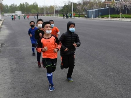China - April oder Mai 2020:
                              Maskenkinder müssen mit Masken Runden
                              rennen