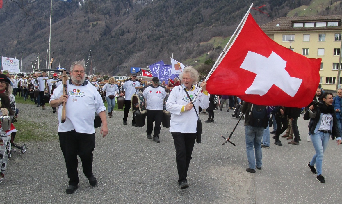 Der R�ckmarsch der Demo in Brunnen:
                  Freiheitstrychler mit Armbrust und Schweizer Fahne,
                  Zoom