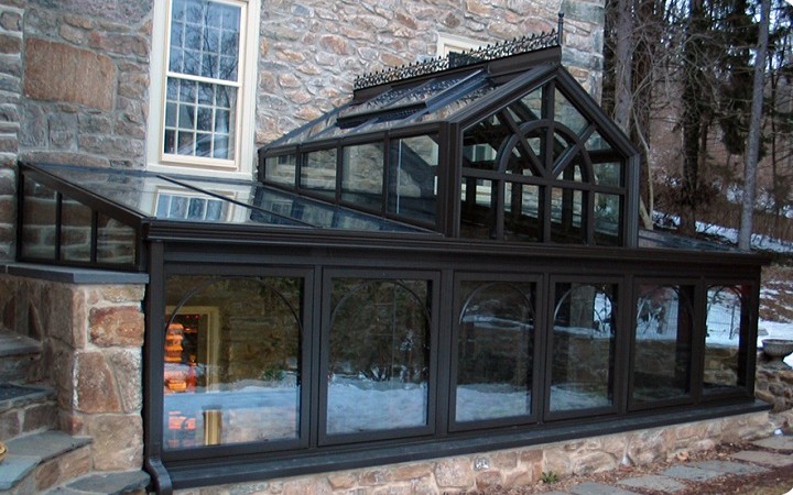 Angebautes Grubengew�chshaus in Schwarz
                            als Erweiterung eines Hauses an eine rohe
                            Steinmauer - sehr energieeffizient.
