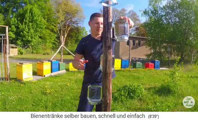 Bienentr�nke aus Senfgurkenglas 09:
                Die Bienentr�nken werden an einem Pfahl an HT-Schellen
                umgekehrt aufgestellt, im Hintergrund sieht man die
                Bienenv�lker