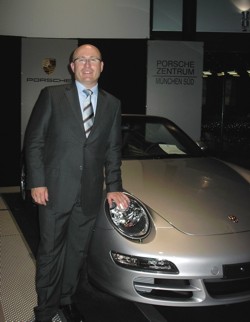 Aberraci�n del ego con adicci�n
                            de carro: hombre blanco con terno y corbata
                            con un Porsche