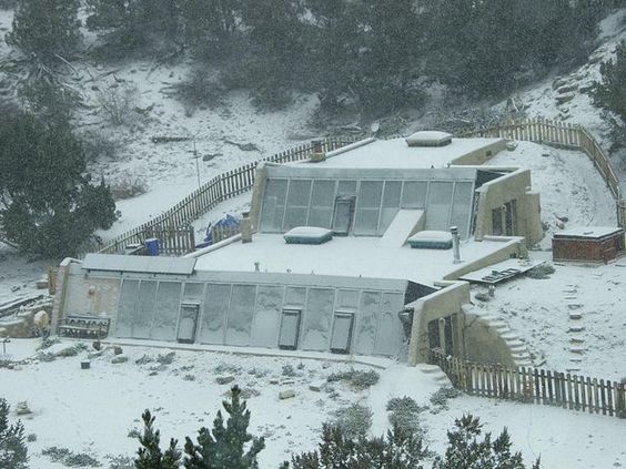 Staggered double earthship barely
                    visible in winter