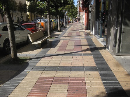 Trottoir / B�rgersteig in
                            gerillten Platten gelb-rot mit schwarzen
                            B�ndern und Sitzbank