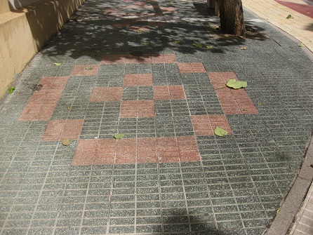 Kleiner Platz mit gr�nen Gartensteinen,
                    rotem Muster und gelbem Trottoir in gerillten
                    Platten, Zoom