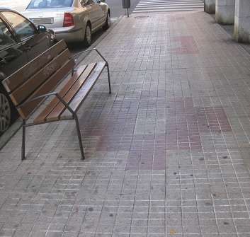 Trottoir /
                        B�rgersteig in gerillten Platten mit gelb-rotem
                        Muster