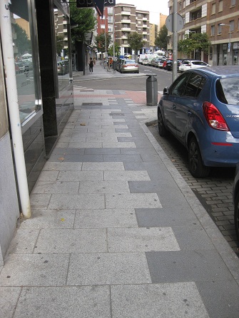 Trottoir / B�rgersteig in weissen Platten
                        mit schwarzen B�ndern und Zahnradband