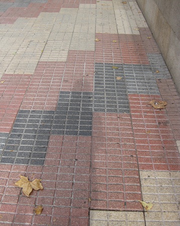 Trottoir / B�rgersteig in gerillten, weissen
                    Platten mit diagonalen B�ndern in rot-schwarz, Zoom