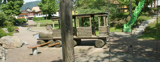 Train engine made of wood with a roof
                            and a trailer on the playground of Thun,
                            Switzerland