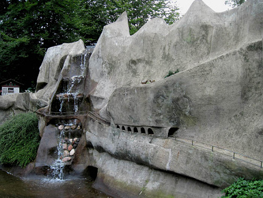 Märchenwald
                            Ibbenbüren 07, ein Märchenfelsen mit Galerie
                            und Wasserfall imitiert eine Schlucht Märchenwald Ibbenbüren 07, ein
                            Märchenfelsen mit Galerie und Wasserfall
                            imitiert eine Schlucht