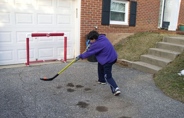 Strassenhockey (Street Hockey) 02 mit
                            orangem Ball vor einem Garagentor, ohne
                            Ortsangabe